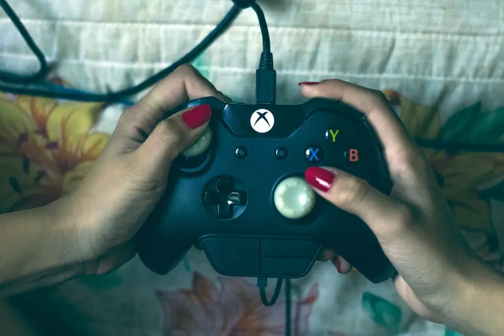Hand with red painted nails holding Xbox 360 game controller